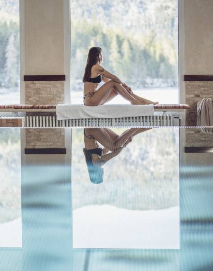 Frau sitzt am Indoorpool mit Blick auf den Eibsee
