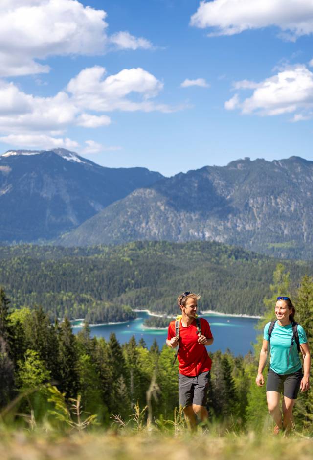 Mann und Frau beim Wandern Richtung Zuspitze mit dem Eibsee im Hintergrund