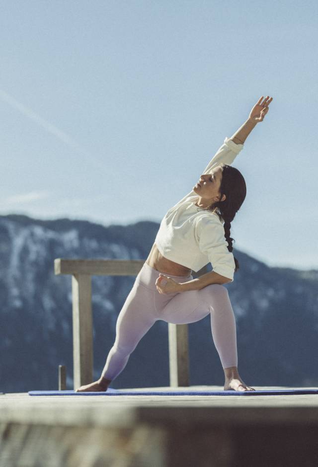 Frau praktiziert Yoga auf dem Steg