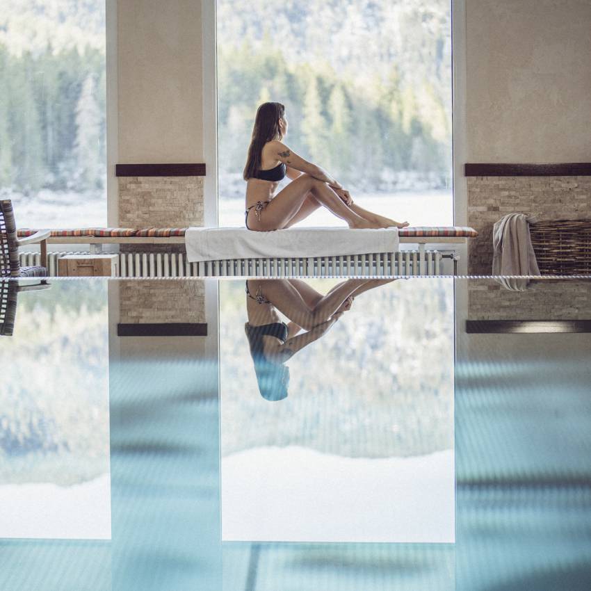 Frau sitzt am Indoorpool mit Blick auf den Eibsee