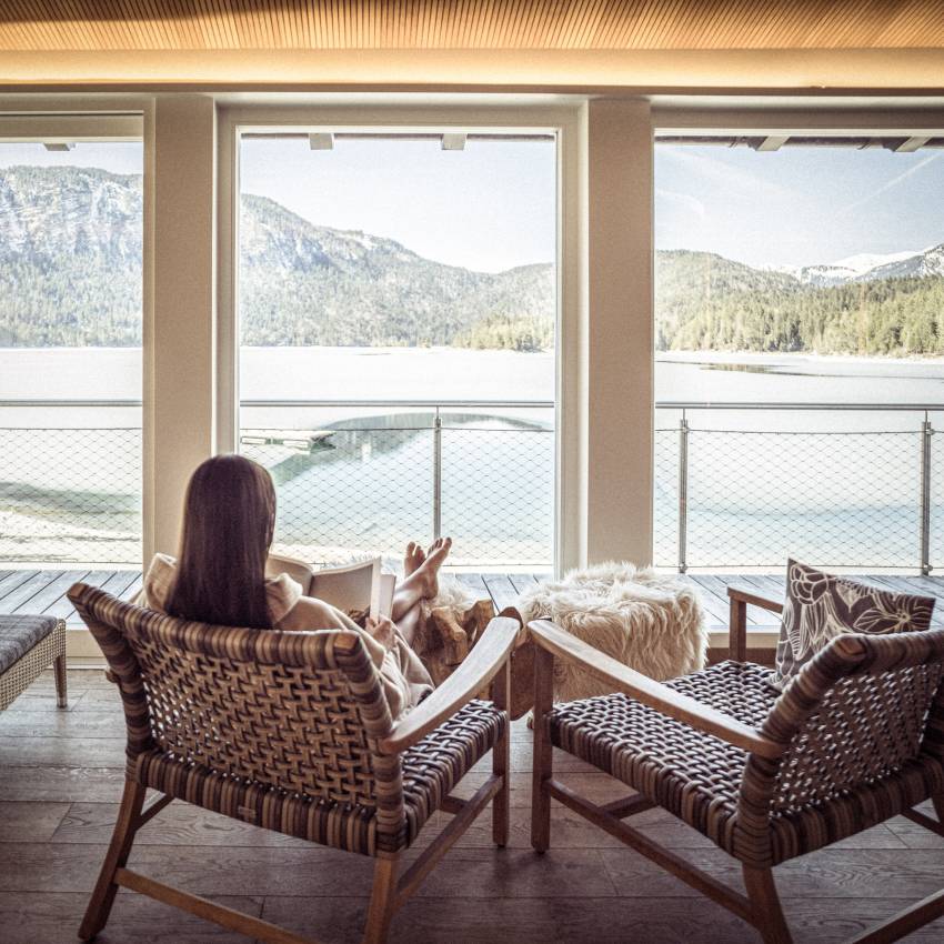 Frau entspannt im Ruheraum mit Blick auf den Eibsee