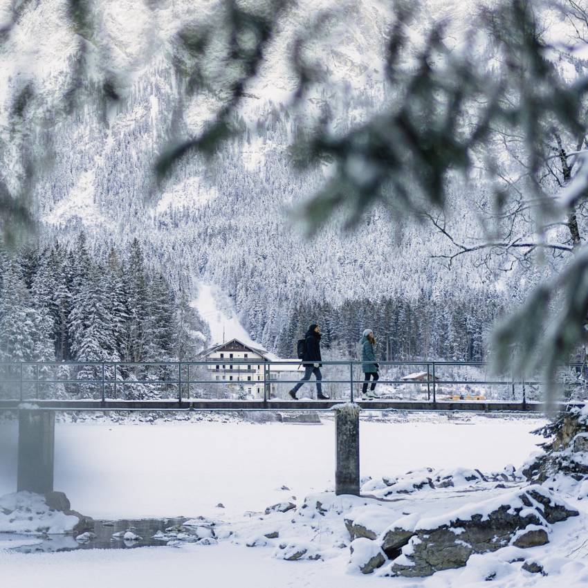 Personen laufen über Steg am Eibsee