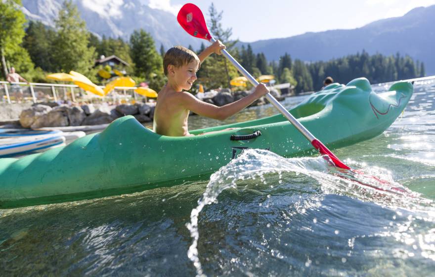 Kind paddelt im Kajak auf dem Eibsee