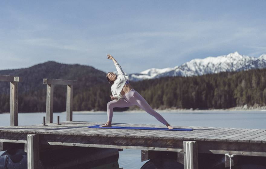 Frau macht Yoga auf dem Steg zum Eibsee