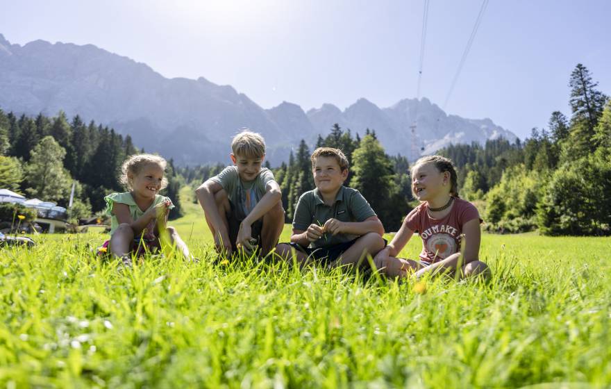 Kinder sitzen im Sommer auf einer Wiese