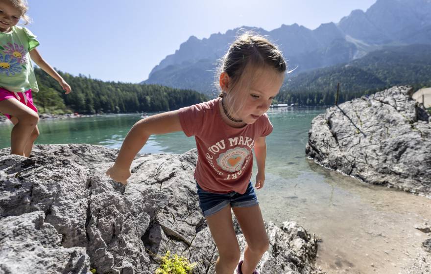 Kind läuft über Steine am Eibsee