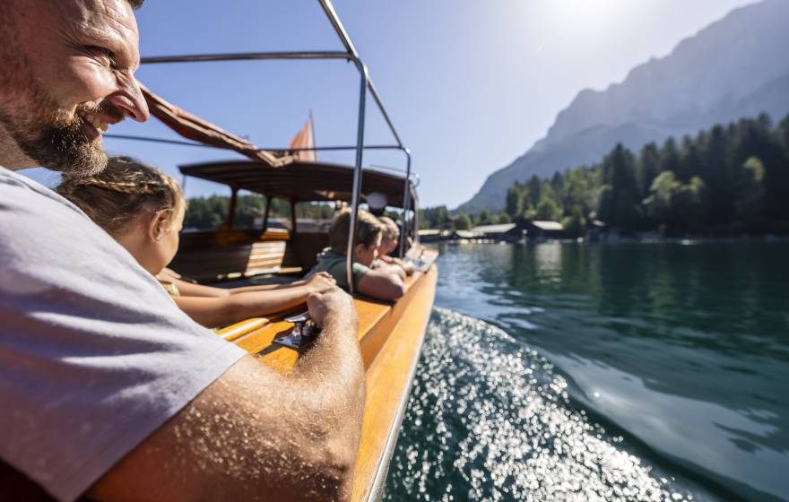 Familie fährt mit einem Motorboot über den Eibsee