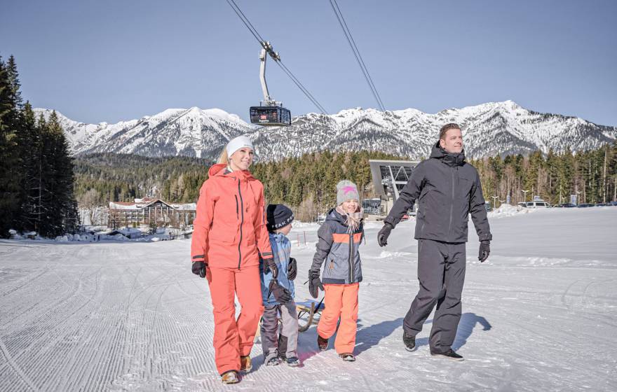 Familie läuft in Schneeanzügen über Skipiste
