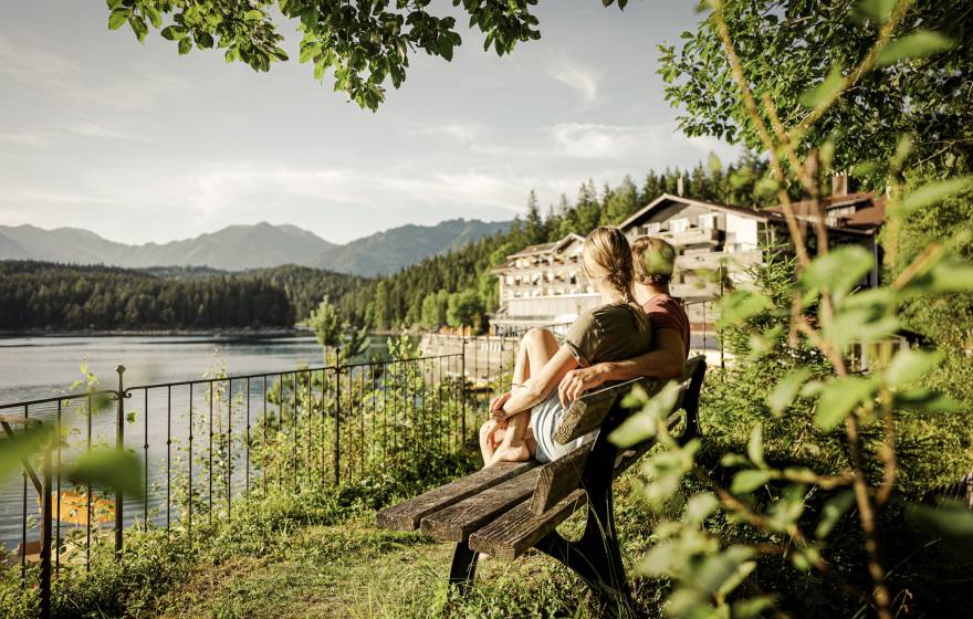 Paar sitzt auf einer Bank mit Blick auf den Eibsee