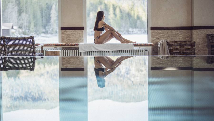 Frau sitzt am Indoorpool mit Blick auf den Eibsee