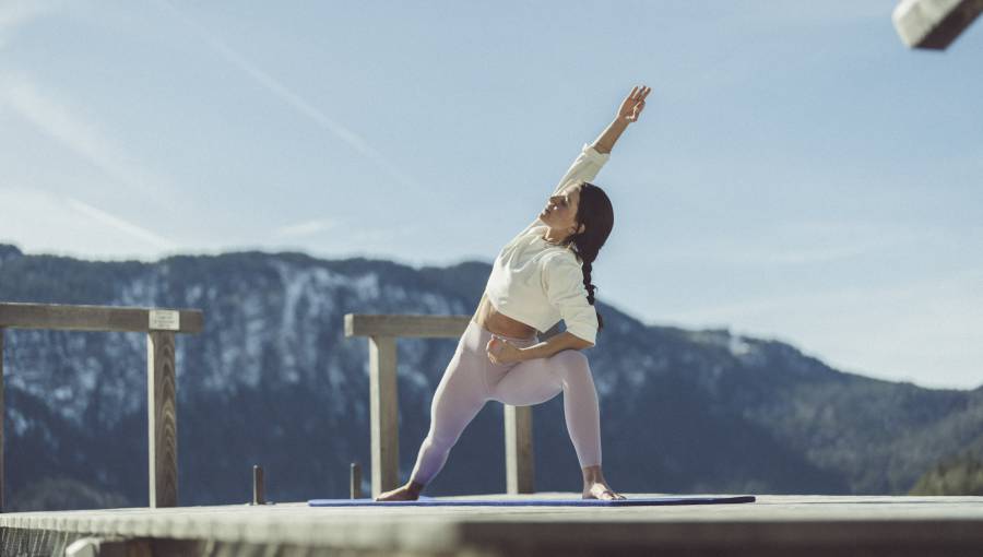 Frau praktiziert Yoga auf dem Steg