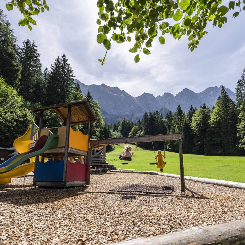 Kinder schaukeln auf einem Spielplatz in Bayern