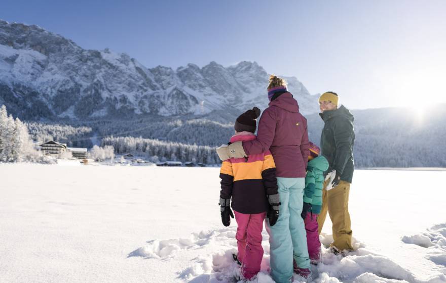 Familie im Schnee mit Blick auf das Eibsee Hotel