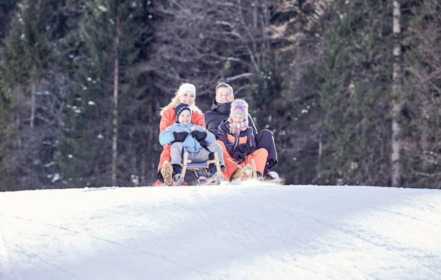 Familie beim Rodeln im Schnee