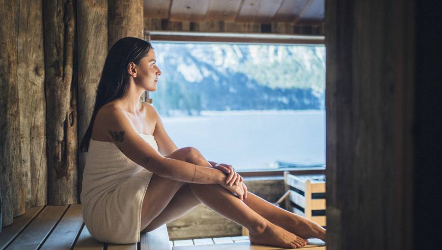 Frau sitzt in der Sauna mit Blick auf den Eibsee